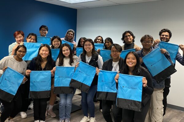On AASAP's opening day, students holding blue and gray bags stand in front of a blue and white wall.