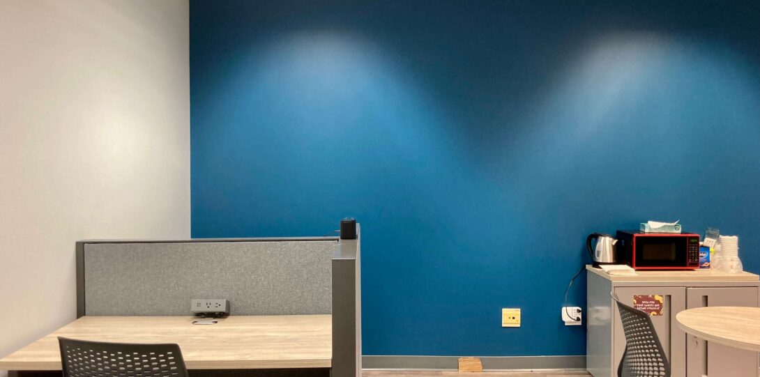 Blue wall facing a cubicle desk and a closet with a red microwave on the right. This shows the left side of the room.