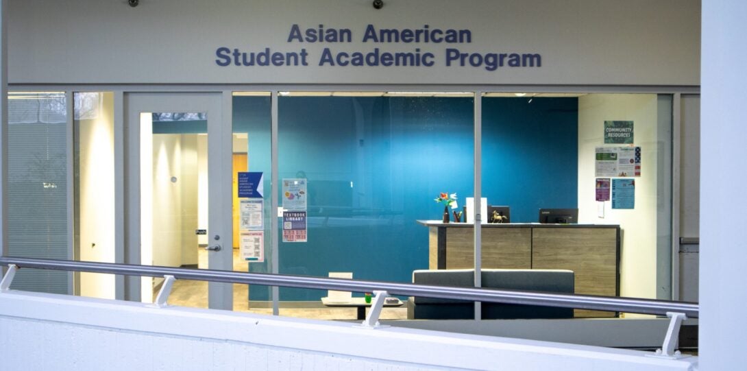 Front of the AASAP space, showing a blue wall with a light brown desk and fliers on the window.